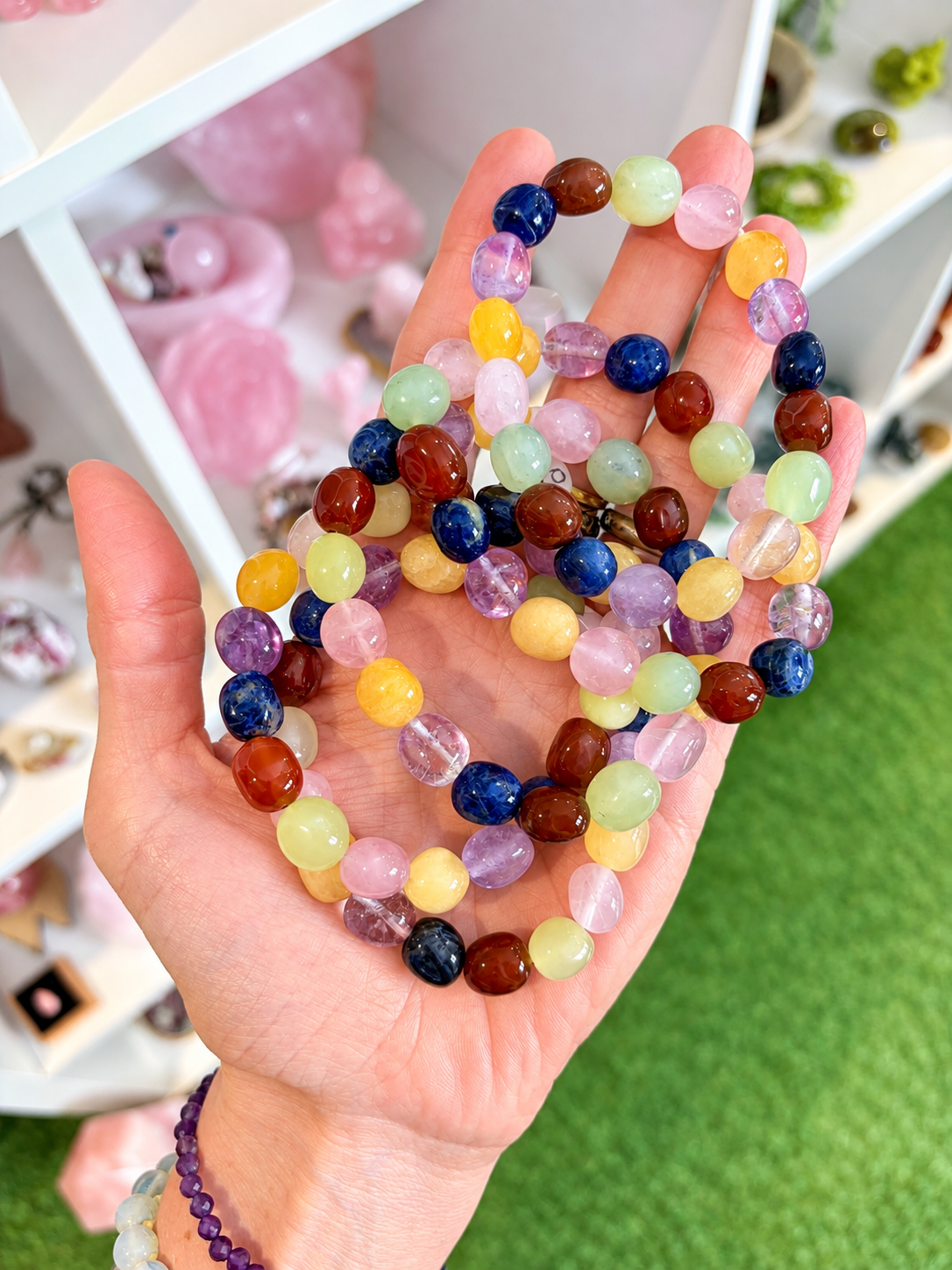 Colourful mixed gemstone chakra bracelets displayed across a hand 