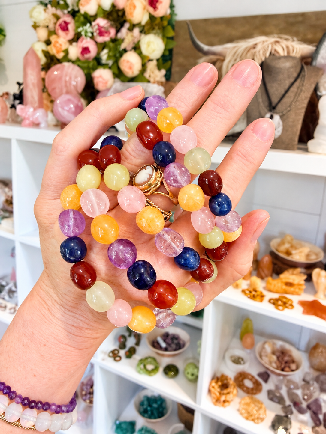Hand holding a colourful mixed gemstone chakra bracelet with natural crystal beads